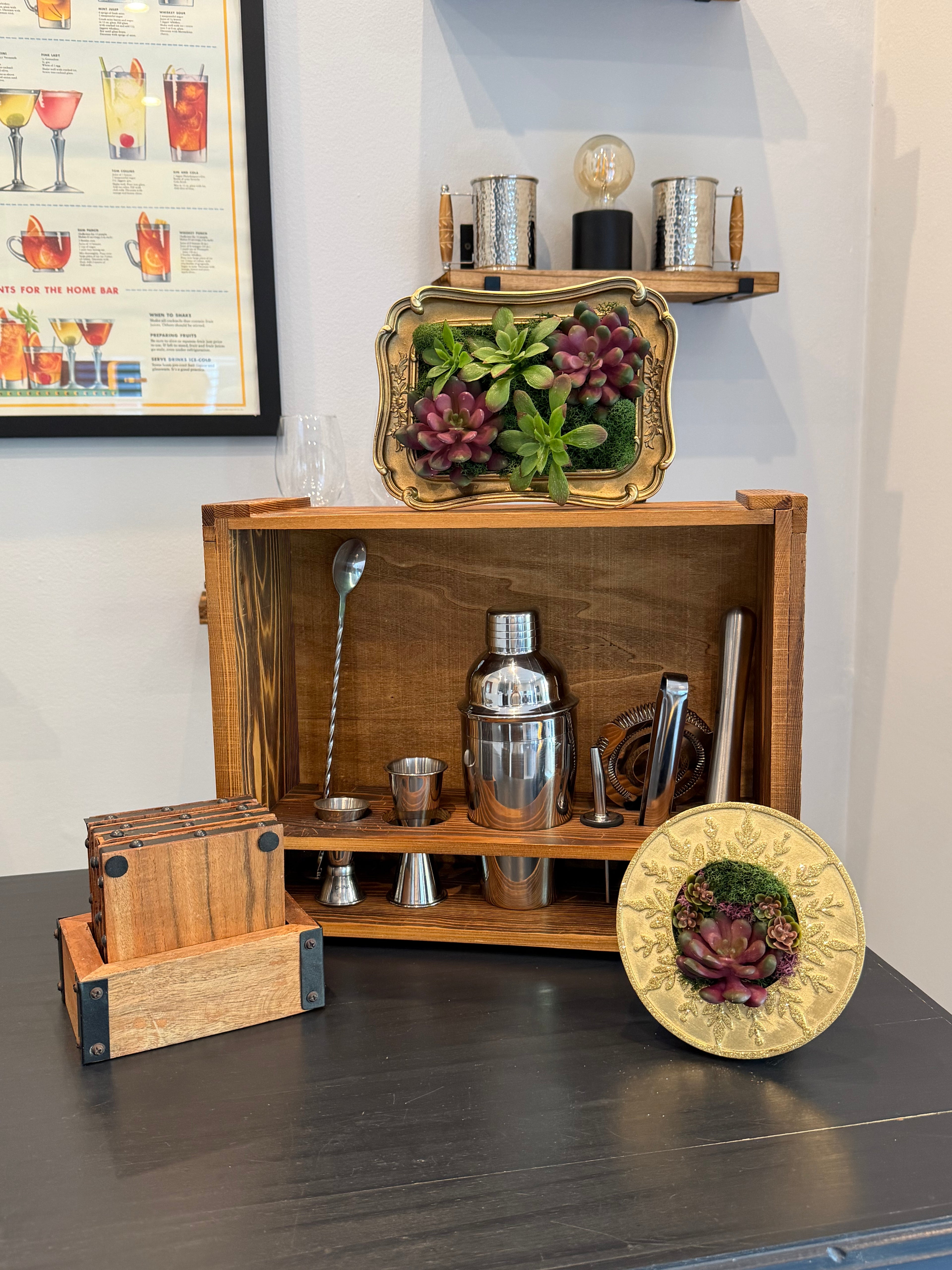 Wooden bar cart with cocktail-making tools and decorative items on a dark surface.