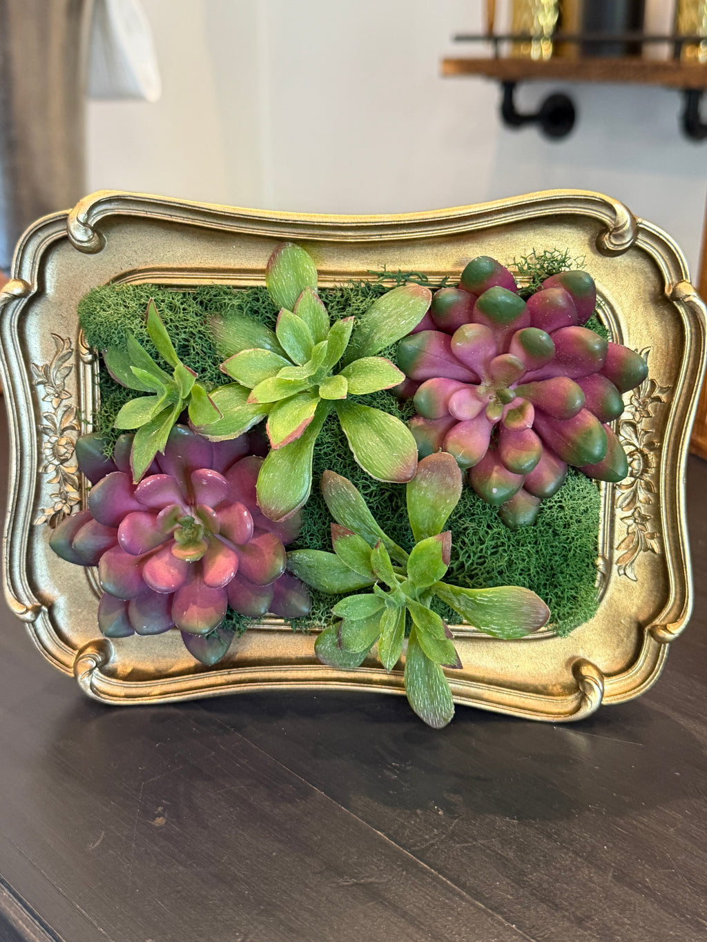 Decorative tray with succulents and greenery on a wooden surface