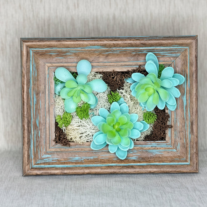 Decorative wall art with succulent plants in a wooden frame on a neutral background