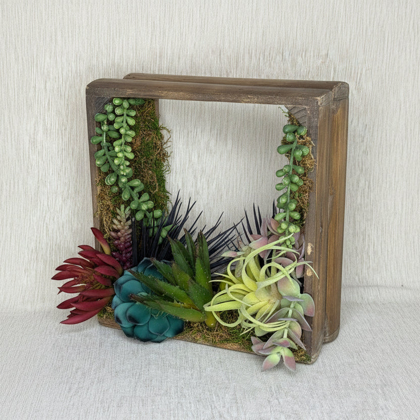 Decorative wooden box with artificial plants on a light background